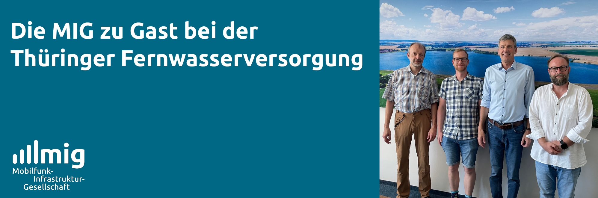 Vier Männer stehen vor einem Panoramabild einer Talsperre.