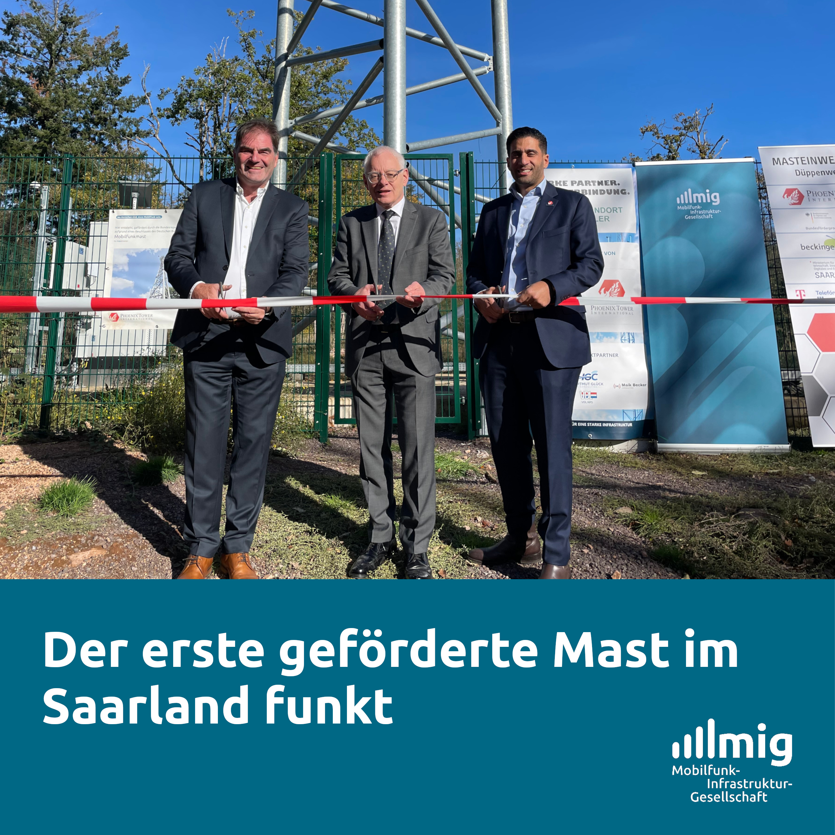 Blauer Himmel, drei Männer stehen am Fuß eines Mobilfunkmastes in Stahlgitterbauweise und schneiden fröhlich lächelnd ein Absperrband durch.